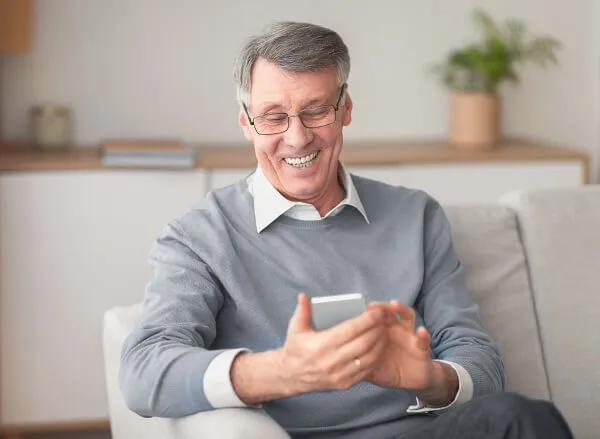 Homem sorrindo para o celular por encontrar uma advogada previdenciária para sua aposentadoria.