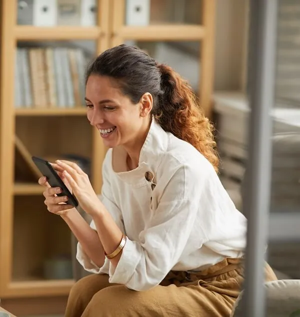 Mulher feliz olhando para o celular com a possibilidade de averbação de aposentadoria.